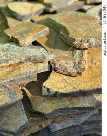 Natural stone slabs stacked in sunlight, perfect for use as a rustic textured background 134682045