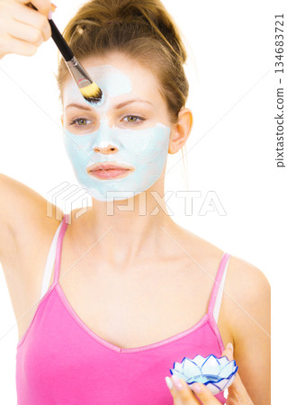 Girl apply green mud mask to face Girl apply green mud mask to face 134683721