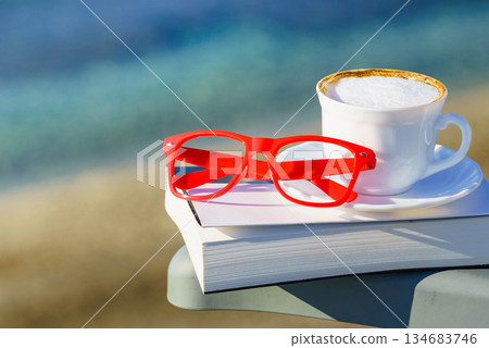 Coffee cup and book on sea coast. Relax 134683746