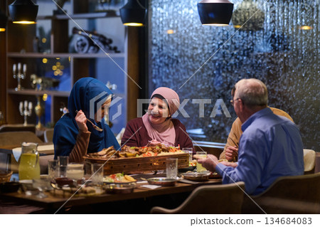 Muslim family enjoying iftar in restaurant with Ramadan decorations and warm lighting 134684083