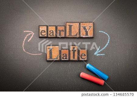 Early vs Late Concept with Wooden Letter Blocks and Chalk Arrows on Blackboard 134685570