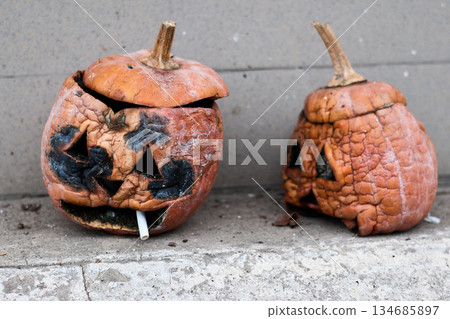 Sad, decaying jack-o'-lanterns with cigarette, forgotten after Halloween and left to rot. 134685897