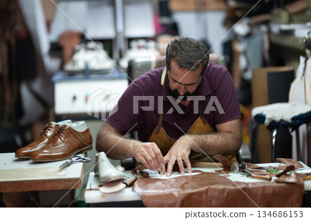 Shoemaker at work in a leather workshop crafting brown dress shoes with precision Shoemaker at work in a leather workshop crafting brown dress shoes with precision 134686153