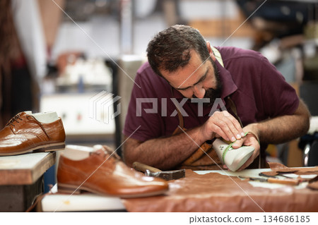 Shoemaker crafting leather dress shoes in workshop, focused on detail and craftsmanship Shoemaker crafting leather dress shoes in workshop, focused on detail and craftsmanship 134686185