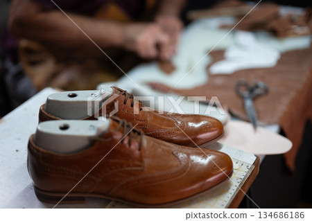 Brown leather dress shoes on lasts at a cobbler's workshop during repair and craftsmanship Brown leather dress shoes on lasts at a cobbler's workshop during repair and craftsmanship 134686186