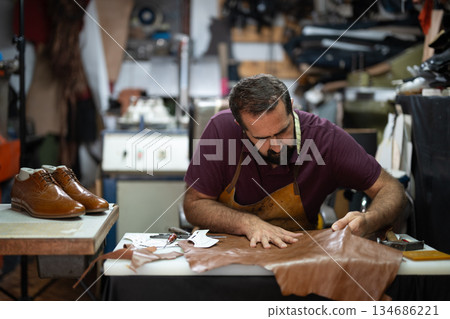 Cobbler at work shaping leather in a busy workshop, crafting handmade shoes with care. Cobbler at work shaping leather in a busy workshop, crafting handmade shoes with care. 134686221