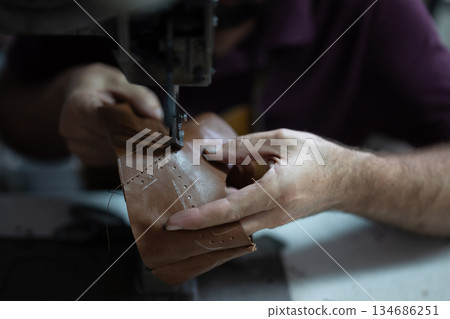 Craftsman sewing leather by hand with a sewing machine, focusing on stitching details 134686251