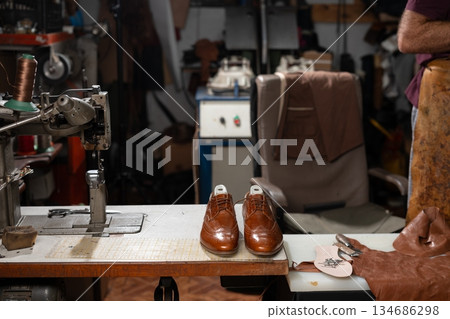 Craftsman shoemaker workstation with polished brown oxford shoes on sewing table Craftsman shoemaker workstation with polished brown oxford shoes on sewing table 134686298