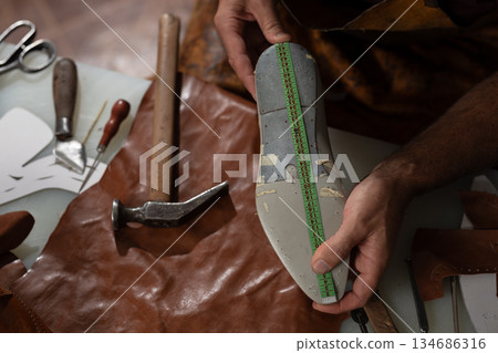 Leather shoemaking in progress: measuring an insole with tape amid tools and leather scraps 134686316