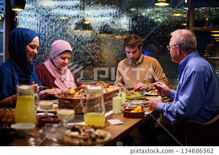 Muslim family breaks fast together in restaurant during Ramadan meal with traditional decorations and warm lighting Muslim family breaks fast together in restaurant during Ramadan meal with traditional decorations and warm lighting 134686362