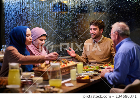 Family gathering during iftar in a restaurant with Ramadan decorations and warm lighting Family gathering during iftar in a restaurant with Ramadan decorations and warm lighting 134686371