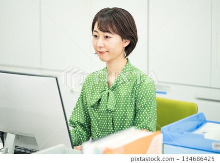 Young female employee working at office desk 134686425