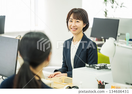 Young career woman talking to a colleague in the office Young career woman talking to a colleague in the office 134686431