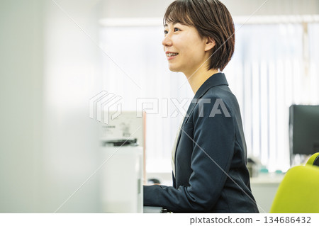 在辦公室做案頭工作的年輕女子 在辦公室做案頭工作的年輕女子 134686432