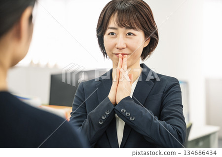 一位女士在工作中向同事尋求協助。 一位女士在工作中向同事尋求協助。 134686434