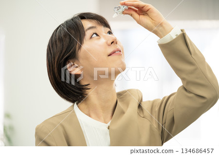 年輕女子在辦公室滴眼藥水 年輕女子在辦公室滴眼藥水 134686457