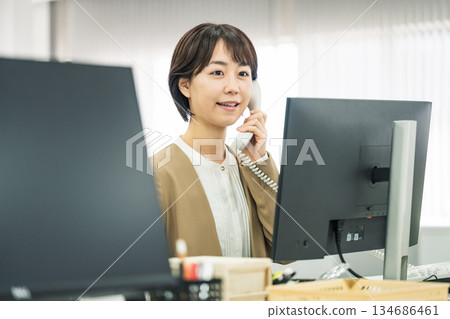 Young woman answering the phone in the office 134686461