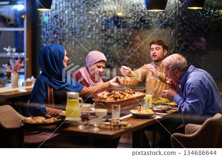 Muslim family enjoying iftar meal together in a restaurant during Ramadan with decorations and warm atmosphere Muslim family enjoying iftar meal together in a restaurant during Ramadan with decorations and warm atmosphere 134686644