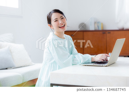 A woman using a computer in the living room 134687745