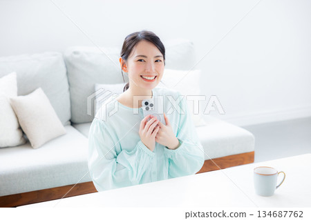 A woman who uses a smartphone in a room A woman who uses a smartphone in a room 134687762