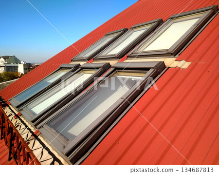 Red tiled house roof with attic windows. Roofing construction, window installation, modern architecture concept. 134687813