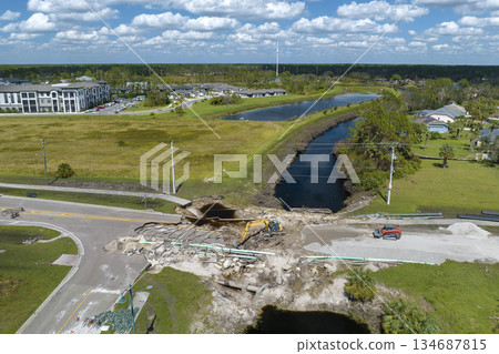 Reconstruction of damaged road bridge destroyed by river after flood water washed away asphalt. Rebuilding of ruined transportation infrastructure 134687815