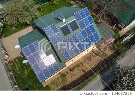 Private home roof covered with solar photovoltaic panels for generating of clean ecological electric energy in suburban rural town area. Concept of autonomous house Private home roof covered with solar photovoltaic panels for generating of clean ecological electric energy in suburban rural town area. Concept of autonomous house 134687836