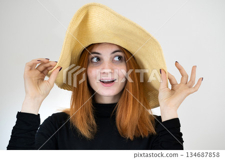 Portrait of funny redhead woman in bag yellow straw hat. Portrait of funny redhead woman in bag yellow straw hat. 134687858