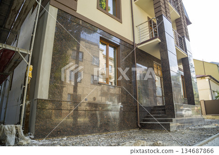 Part of a building facade with the surface of granite wall. Natural stone materials. 134687866