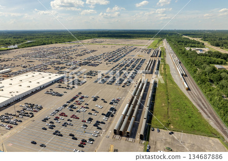 New cars loading on cargo train hauler for worldwide export on automotive factory parking lot. Dealer vehicle inventory business commercial New cars loading on cargo train hauler for worldwide export on automotive factory parking lot. Dealer vehicle inventory business commercial 134687886