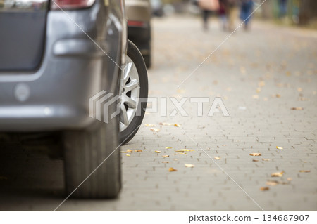 Modern silver car parked on paved sunny quiet suburban street on sunny day. Transportation, comfort, speed concept. Modern silver car parked on paved sunny quiet suburban street on sunny day. Transportation, comfort, speed concept. 134687907