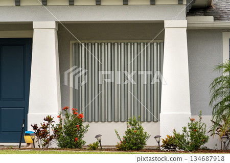 Metal storm shutters installed on residential windows in Florida as protection against hurricanes. Preventive safety measure before natural disaster Metal storm shutters installed on residential windows in Florida as protection against hurricanes. Preventive safety measure before natural disaster 134687918