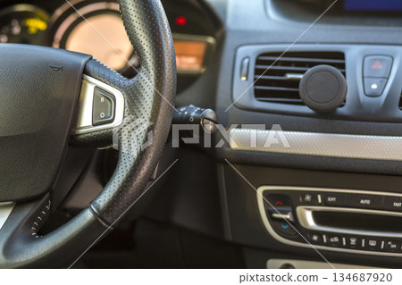 Luxurious car interior. Dashboard and steering wheel in black gray color. Transportation, design, modern technology concept. 134687920