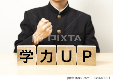 一名男學生舉起寫著「提高學業成績」的方塊，做出握拳慶祝的手勢。 134689021