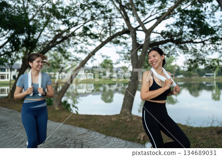 Two happy women going for sunrise running. Women in track suits running at park 134689031