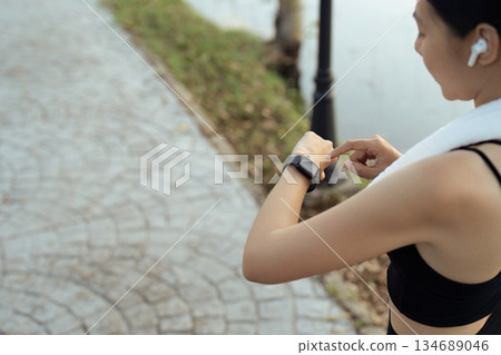Sport young woman looking at smartwatch on her wrist, tracking fitness activity during training outdoors Sport young woman looking at smartwatch on her wrist, tracking fitness activity during training outdoors 134689046
