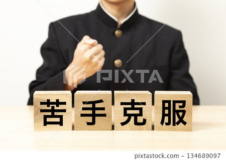 一名男學生舉起寫著「克服你的弱點」的積木，做出握拳慶祝的手勢。 134689097