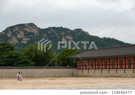Tourists Strolling Along the Historic Stone Wall of Gyeongbokgung Palace with Ansan Mountain Towering in the Background in Seoul 134690477
