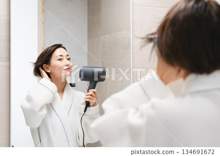 一位女士正在用吹風機吹乾頭髮。美麗的畫面 一位女士正在用吹風機吹乾頭髮。美麗的畫面 134691672