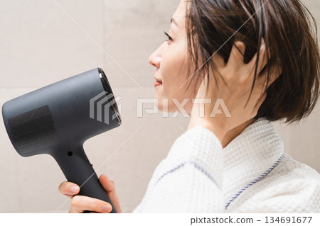 一位女士正在用吹風機吹乾頭髮。美麗的畫面 一位女士正在用吹風機吹乾頭髮。美麗的畫面 134691677