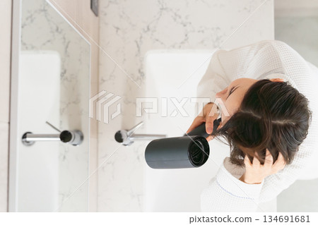 一位女士正在用吹風機吹乾頭髮。美麗的畫面 一位女士正在用吹風機吹乾頭髮。美麗的畫面 134691681