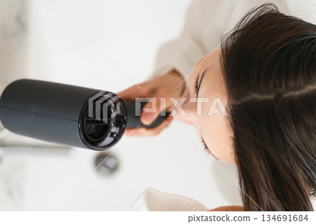一位女士正在用吹風機吹乾頭髮。美麗的畫面 一位女士正在用吹風機吹乾頭髮。美麗的畫面 134691684