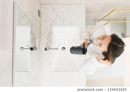 A woman drying her hair with a hair dryer Beauty image A woman drying her hair with a hair dryer Beauty image 134691685
