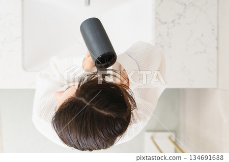 A woman drying her hair with a hair dryer Beauty image 134691688