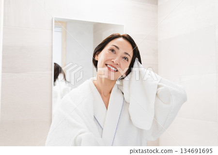 Woman wiping her hair with a towel Lifestyle image Woman wiping her hair with a towel Lifestyle image 134691695