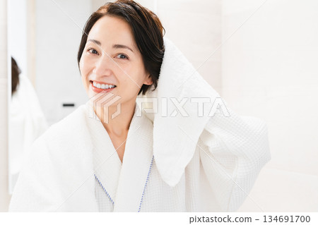 Woman wiping her hair with a towel Lifestyle image Woman wiping her hair with a towel Lifestyle image 134691700