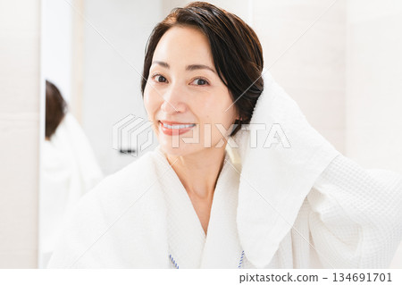 Woman wiping her hair with a towel Lifestyle image Woman wiping her hair with a towel Lifestyle image 134691701