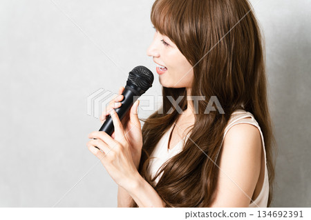 一位女士拿著麥克風唱歌（生活照） 134692391