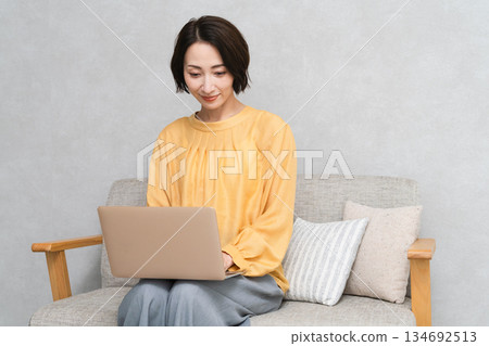 Woman sitting on the sofa and using a laptop Lifestyle image 134692513