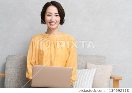 Woman sitting on the sofa and using a laptop Lifestyle image 134692518